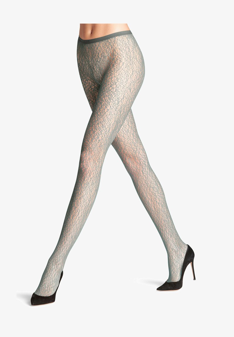 Przezroczyste zielone rajstopy w wzory z delikatnym koronkowym wzorem i gładkim wykończeniem, zestawione z czarnymi szpilkami.