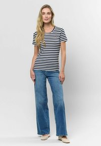 Svītraina T-kreklu tumši zila un balta, ar īsām piedurknēm, apaļu dekoltē, ar mazu logo. Kombinēta ar gaiši ziliem platām biksēm.