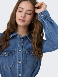 Denim shirt featuring a classic collar, button front, two chest pockets, and long sleeves with buttoned cuffs in medium blue wash.