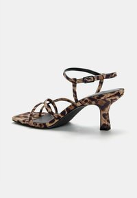 Talons de sandale à imprimé léopard avec un bout carré, des brides fines et un talon bloc de hauteur intermédiaire. Le matériau semble texturé et ressemblant au suède.