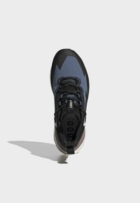 Scarpa sportiva blu e nera con parte superiore lavorata, lacci neri e suola ammortizzata. Presenta un accento bianco vicino al tallone e un logo.