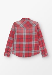 Červeno-šedá kostkovaná košile s dlouhými rukávy, knoflíkovými manžetami, zakřiveným lemem a detailem na hřbetu. Vyrobena z měkké tkaniny s hladkou strukturou.