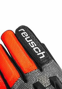 Black and orange goalie gloves featuring textured grip surfaces, contrasting color accents, and a prominent "Reusch" logo on the wrist.