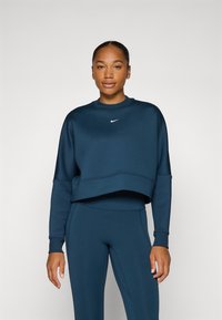 Sweatshirt cropped bleu marine avec un col rond, doté de manches longues et d'un petit logo blanc sur la poitrine. Texture lisse.