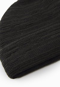 Sort strikket hue med en ribbet tekstur. Blødt materiale, rund top og foldet kant. Simpelt design uden yderligere udsmykninger.