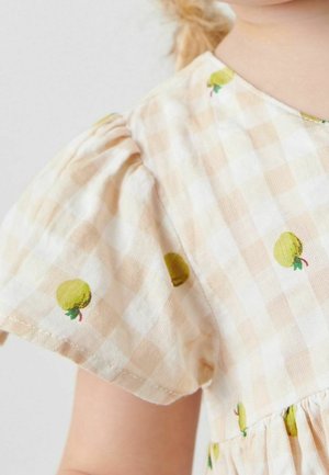 Robe à manches bouffantes en tissu à carreaux beige avec broderie de pommes vertes, dotée d'une taille froncée et d'un tissu en coton doux et texturé.