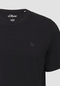 Zwarte katoenen t-shirt met een ronde hals, korte mouwen en een klein, reliëflogo op de linkerborst. Gladde textuur.