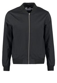 Chaqueta bomber negra con cremallera frontal y puños acanalados. Textura de tela suave, diseño simple y cuello redondo sin adornos.