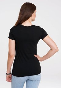 Camiseta negra ajustada de manga corta y cuello redondo, hecha de una tela suave. Se muestra desde la parte de atrás con una textura lisa.