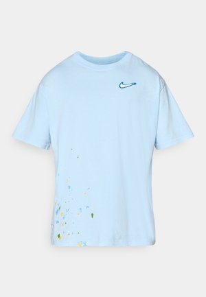Světlemodré bavlněné tričko s krátkým rukávem, s modrým logem Nike a vícebarevným rozpršením na dolní levé straně.
