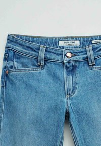 Vaqueros ceñidos cortos azules con botón frontal, pasadores para cinturón y etiqueta que dice "Salsa Jeans Wonder" en la cintura.