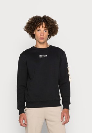 Schwarzes Sweatshirt mit Rundhalsausschnitt, langen Ärmeln und gerippten Bündchen. Verfügt über ein weißes Logo auf der Brust und eine Reißverschlusstasche am Ärmel.