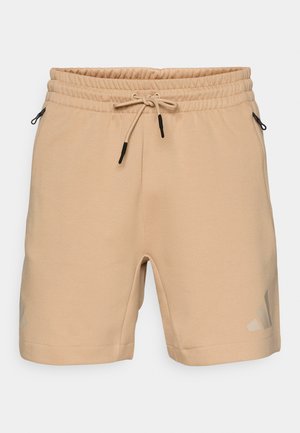 Shorts de sport beiges en tissu doux, avec une taille élastique, un cordon de serrage et des poches latérales. Présente un logo discret.