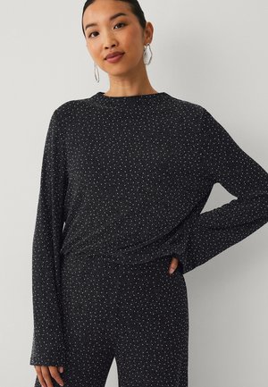 Black long-sleeve top with ribbed texture and white speckles. Features a round neckline and relaxed fit, paired with matching pants.