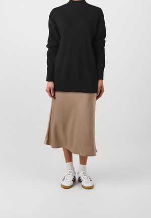 Black turtleneck sweater with ribbed hem, beige satin midi skirt, and white sneakers with black stripes on side, paired with white socks.