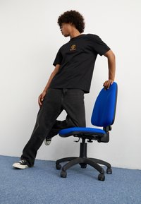 Ergonomischer Bürostuhl mit einem blauen Stoffbezug für Sitzfläche und Rückenlehne, schwarzem Kunststofffuß und fünf Rollen. Höheneinstellbar mit Armlehnen.