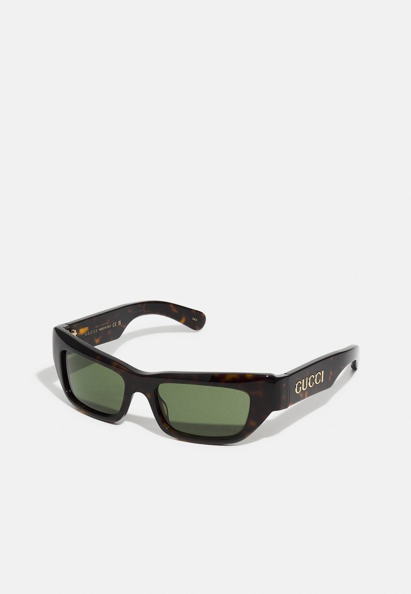 Occhiali da sole tartarugati con lenti verdi. Design della montatura quadrata, con logo dorato sulla tempia. Finitura in plastica liscia.