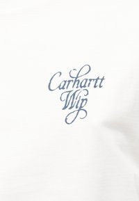 Λευκό ύφασμα με μπλε στυλιζαρισμένο κείμενο "Carhartt Wip" τυπωμένο στο κέντρο.