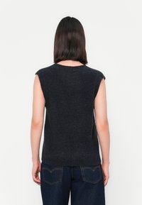Donkergrijze mouwloze gebreide sweater met een ronde halslijn en ribbelzoom, van achteren getoond op een model dat blauwe jeans draagt.