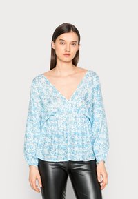 Blusa floral azul claro com decote em V profundo, mangas longas e franzido na cintura. O tecido parece suave e leve.