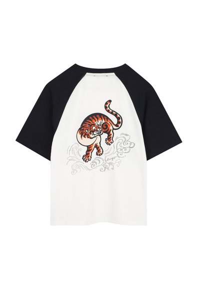 T-shirt blanc à manches courtes avec des manches raglan noires. Présente un graphique de tigre orange avec des accents noirs au dos, entouré de vagues décoratives.