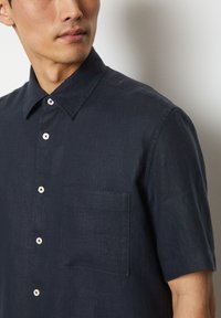 Korte mouwen marineblauwe button-up shirt van een textuurstof, met een borstzak en lichtgekleurde knopen. Eenvoudig kraagontwerp.