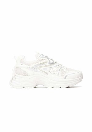 Zapatilla deportiva blanca con suela gruesa, tejido de malla y diseño con cordones, mostrada de lado sobre un fondo blanco.