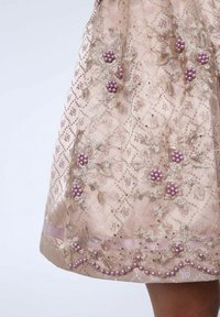 Rosa besticktes Kleid mit floralen Mustern, verziert mit lila Perlen und goldenen Akzenten, strukturiertem Stoff und einer Saumverzierung.