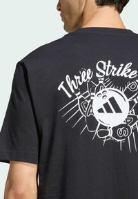 Black cotton t-shirt featuring a large white graphic with "Three Strike" text, a bowling ball, and pins in a striking design on the back.