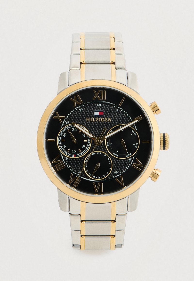Herren-Tommy-Hilfiger-Uhr mit schwarzem Zifferblatt, goldenen römischen Ziffern, drei Teilzifferblättern und einem silbernen und goldenen Metallarmband.