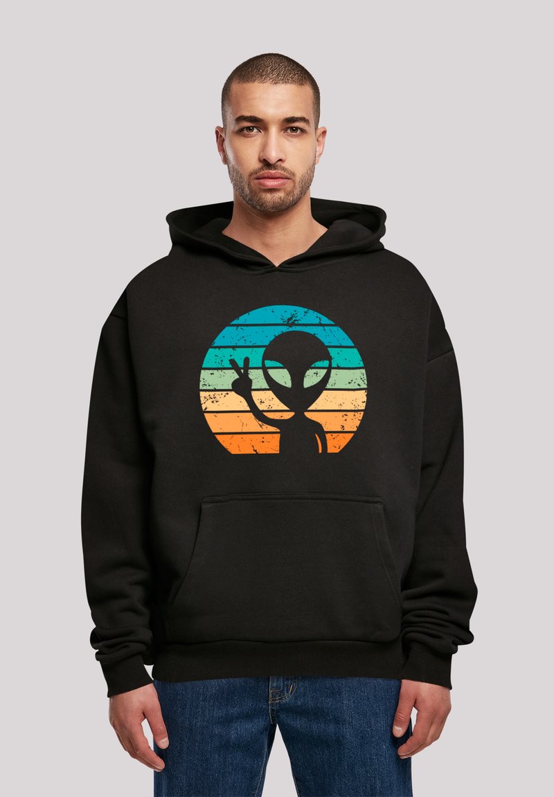 Schwarzer Hoodie mit einer Vordertasche und einer Grafik eines Alien-Silhouetten vor einem Farbverlauf-Hintergrund aus blauen und orangenen Streifen.