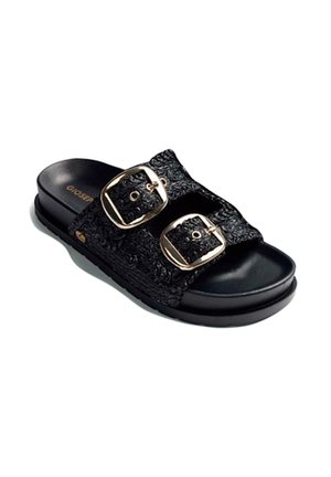 Sandalia negra sin cierre con dos tiras texturizadas y grandes hebillas doradas, con plantilla acolchada y suela plana.