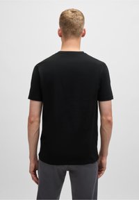 Svart bomulls-t-shirt med korta ärmar och rundad halsringning, med en slät textur och normal passform, sedd från baksidan.