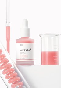 Siero peptide rosa in una bottiglia di vetro con pipetta bianca. Becher di vetro adiacente con liquido rosa e applicatore a spirale rosa.