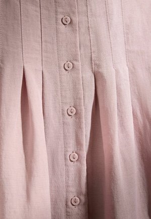 Light pink fabric with vertical pleats and a central row of round, matching buttons sewn with four holes.
