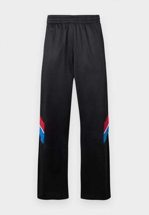 Schwarze Sporthose mit elastischem Bund. Mit rot-blauen diagonalen Streifen an den Außenseiten. Glattes, leichtes Material.