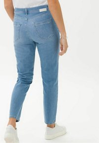 Ljusblå jeans i denim med en smal passform, med bakfickor och medelhög midja. I kombination med vita sneakers.