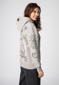 Grijze hoodie met een trekkoord en een voorzak, voorzien van verschillende kleurrijke krabbels, tekst en grafische ontwerpen op de mouwen en de achterkant.