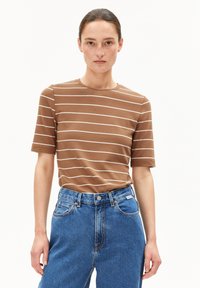 Bruine gestreepte t-shirt met korte mouwen, ronde halslijn, gemaakt van een getextureerde stof, gecombineerd met hoogtaille blauwe spijkerbroek met een knoopsluiting.