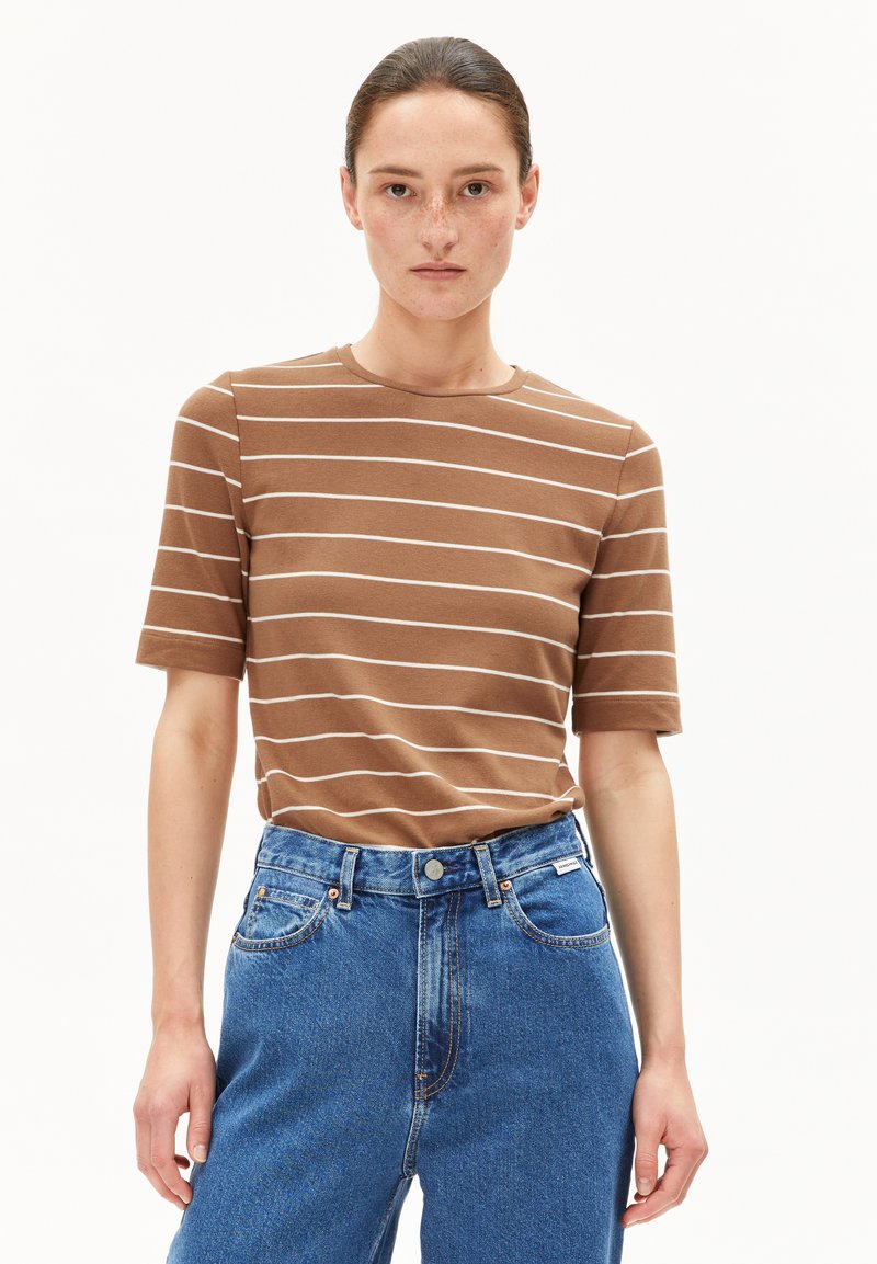 Bruine gestreepte t-shirt met korte mouwen, ronde halslijn, gemaakt van een getextureerde stof, gecombineerd met hoogtaille blauwe spijkerbroek met een knoopsluiting.
