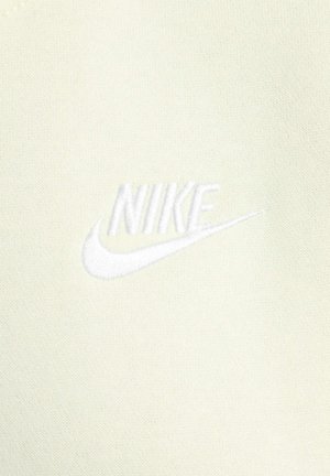 Abbigliamento Nike in un colore crema chiaro con una texture morbida. Presenta un logo ricamato in bianco, centrato sul tessuto.