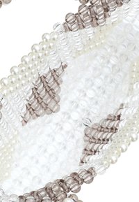 Gyöngyökkel díszített karkötő, amely átlátszó, matt és barna üveggyöngyökből áll, gyöngyök váltakozó mintáival; textúrált, sima felületekkel.