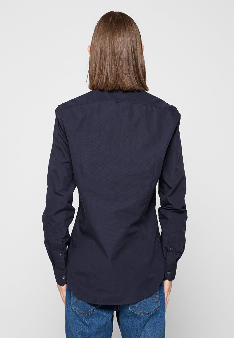 Camicia a maniche lunghe in cotone blu navy con polsini con bottoni, yoke posteriore e orlo curvo, caratterizzata da una texture liscia e una vestibilità sartoriale.