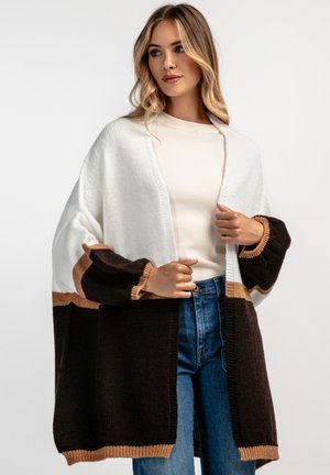 Sweter kardigan w kolorach kremowym, brązowym i tan. Posiada długie rękawy, otwarty przód oraz luźny krój z prążkowanymi akcentami.