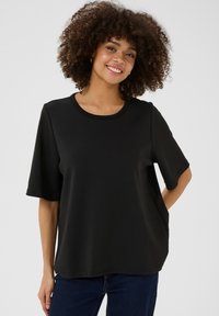 Svart kortärmad skjorta med rund halsringning, tillverkad av mjukt tyg. Har en avslappnad passform och en jämn textur.