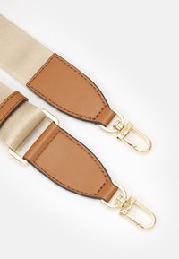 Cintura in tessuto beige con estremità in pelle marrone e ganci girevoli in metallo dorato su sfondo bianco.