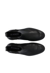 Paire de bottines Chelsea en cuir noir à enfiler avec des panneaux latéraux élastiques et des semelles intérieures estampillées, vues de dessus sur fond blanc.