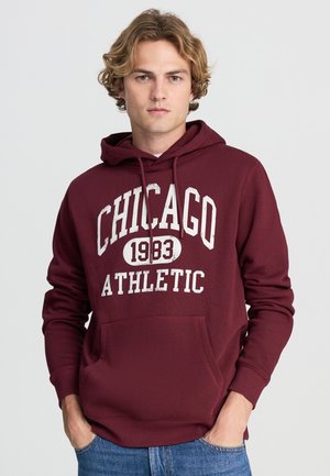 Felpa maroon con tasca frontale, con il testo "CHICAGO 1983 ATHLETIC" in bianco. Tessuto morbido, cappuccio con coulisse e polsini a costine.