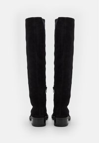 Bottes noires en daim au-dessus du genou avec une finition texturée, dotées d'une fermeture éclair à l'arrière et d'un talon plat noir lisse.