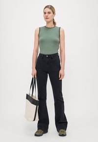 Grønn og hvit stripete ermeløs topp, høy i livet svarte flagrende jeans, lys brun og svart totebag, og grønne joggesko. Enkel design.